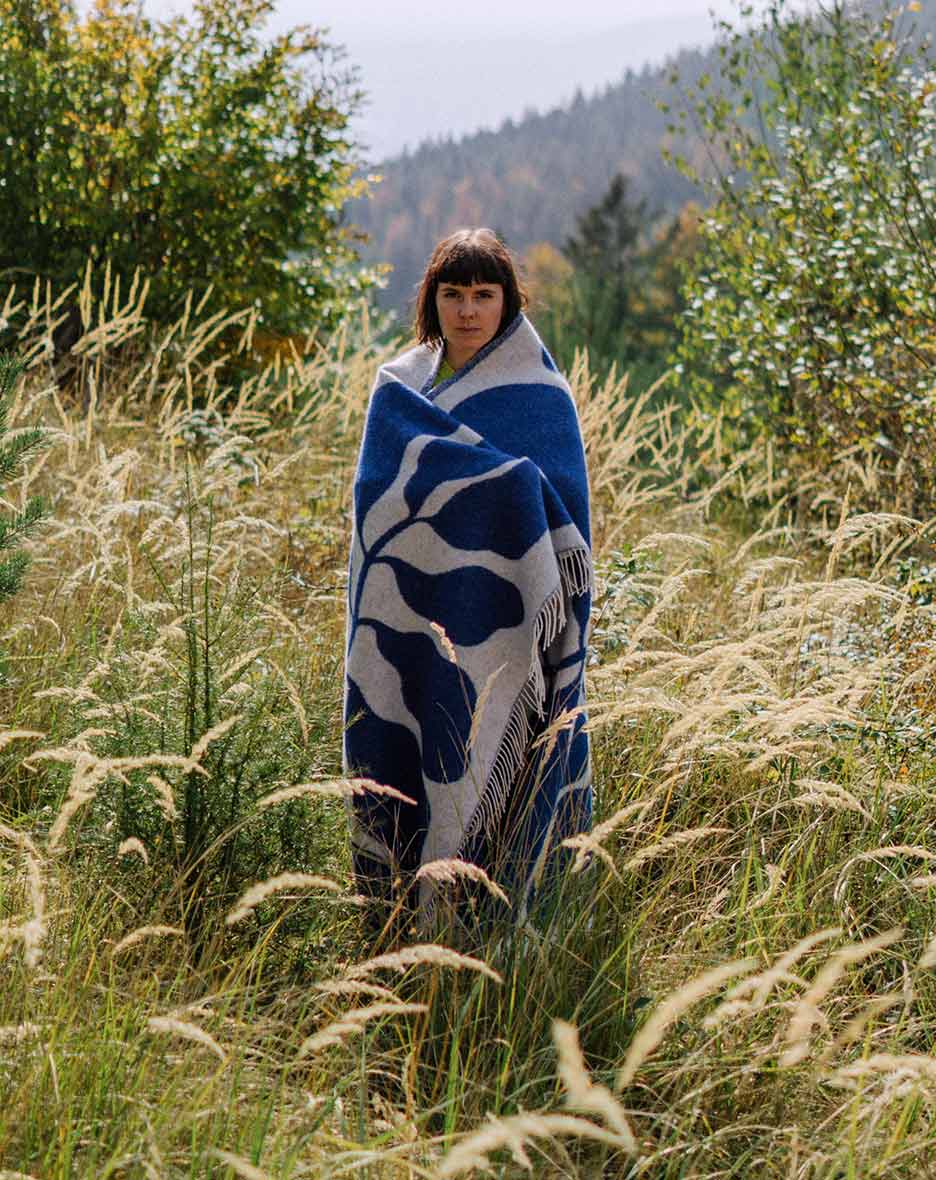 Co-founder of RAWTY Tessa Sophie Huber standing in a field of grass with a blue blanket wrapped around her.