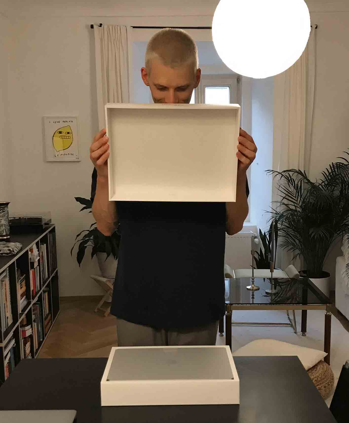 Christian Leban opening the box of his new laptop looking very exciting standing next to the table.