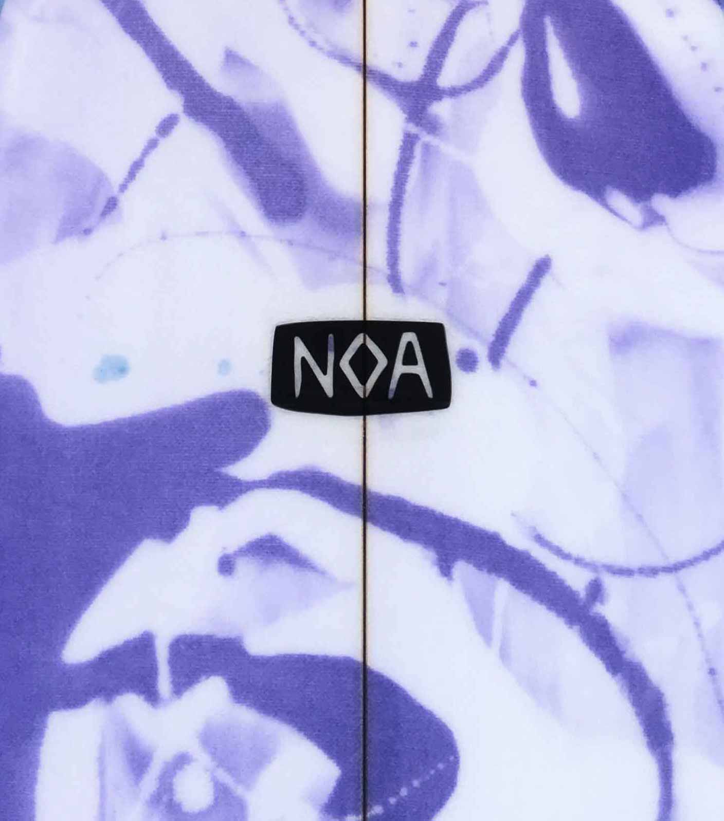 The NOA Surfboards logo on a white surfboards with purple and lavender graffiti-style color swirls.