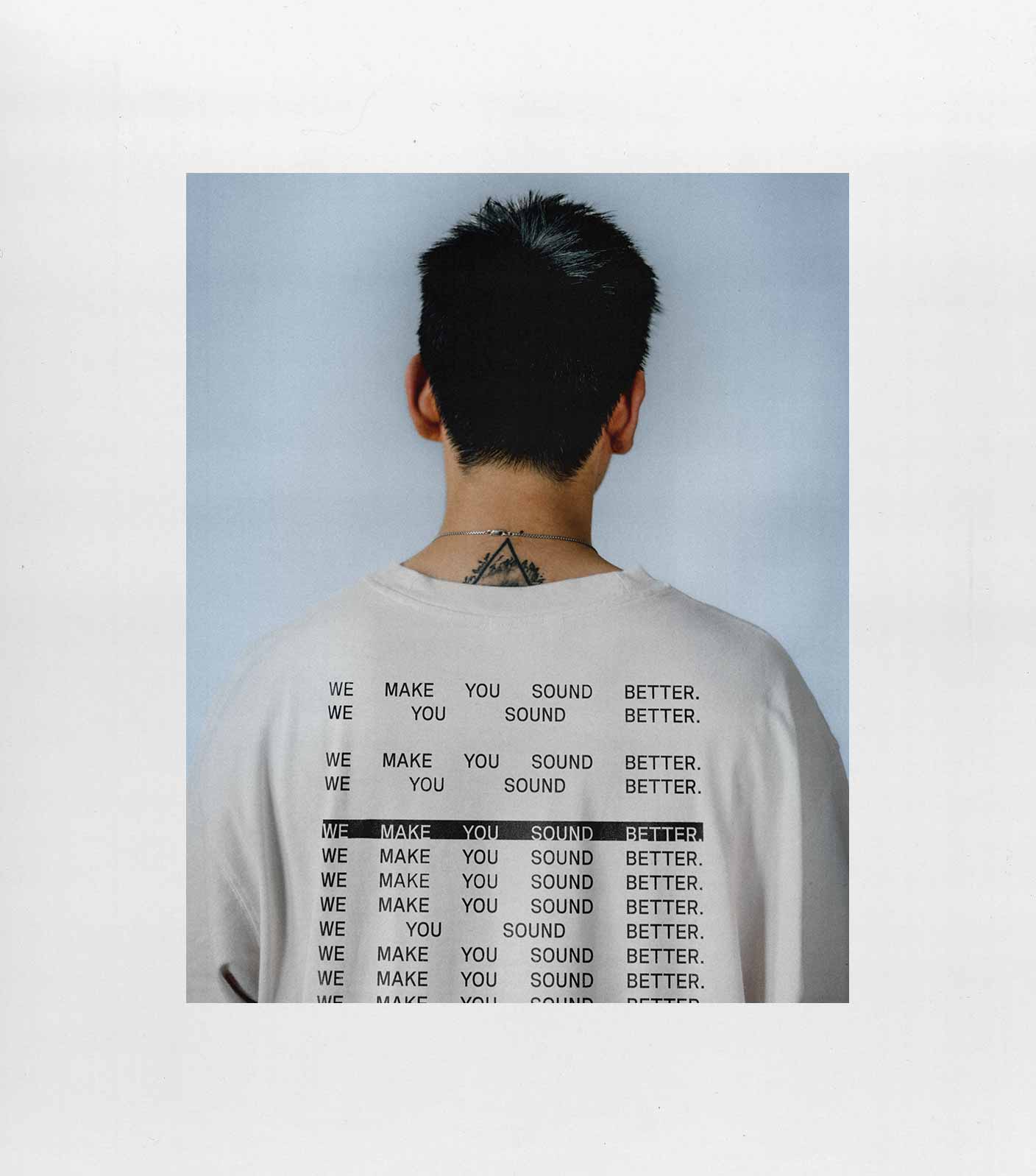The photo shows a portrait of the back of a young man with a white t-shirt with a backprint from unstudios. Shot by Christian Leban.